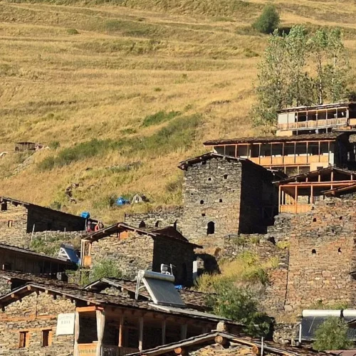 Panoramic view of Dartlo village in Tusheti, Georgia, featuring traditional stone towers and houses on a stepped hillside.