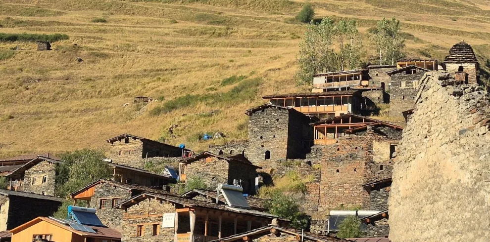 Panoramic view of Dartlo village in Tusheti, Georgia, featuring traditional stone towers and houses on a stepped hillside.