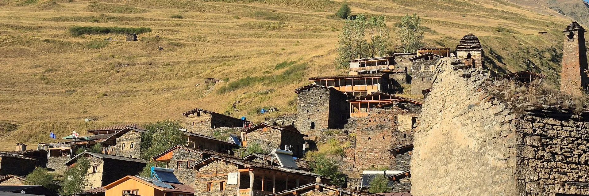 Panoramic view of Dartlo village in Tusheti, Georgia, featuring traditional stone towers and houses on a stepped hillside.