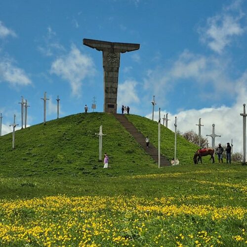 Wide panoramic view of the Didgori Battle Memorial with giant swords on green mountain ridges.