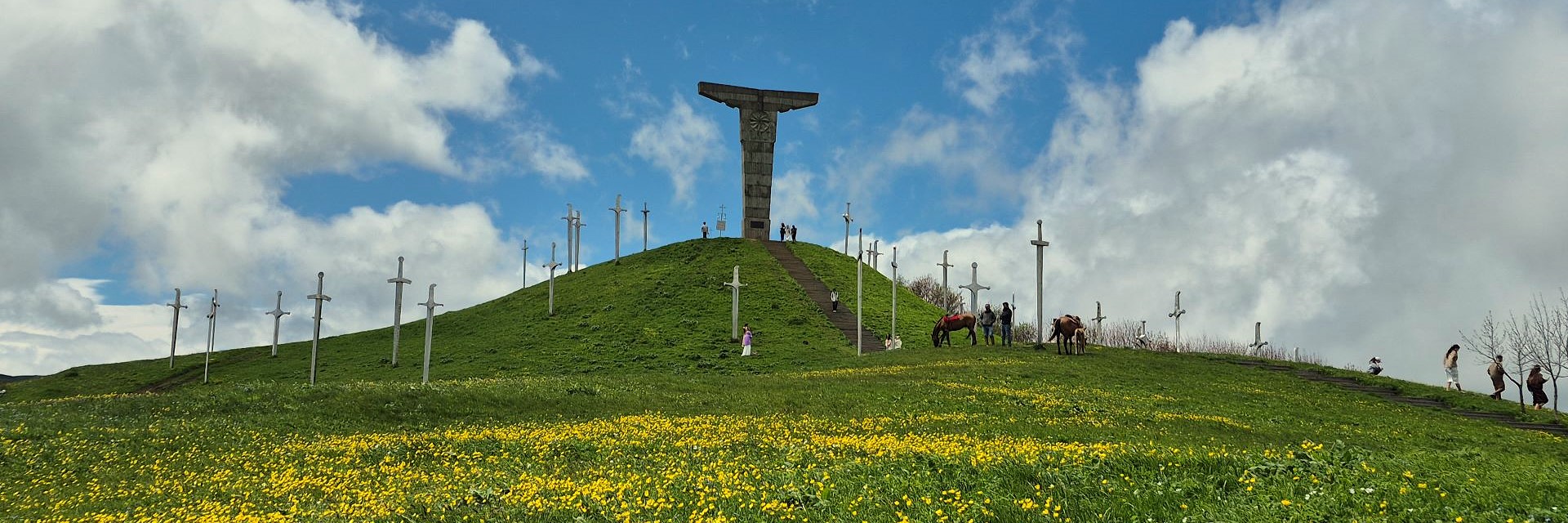 Wide panoramic view of the Didgori Battle Memorial with giant swords on green mountain ridges.