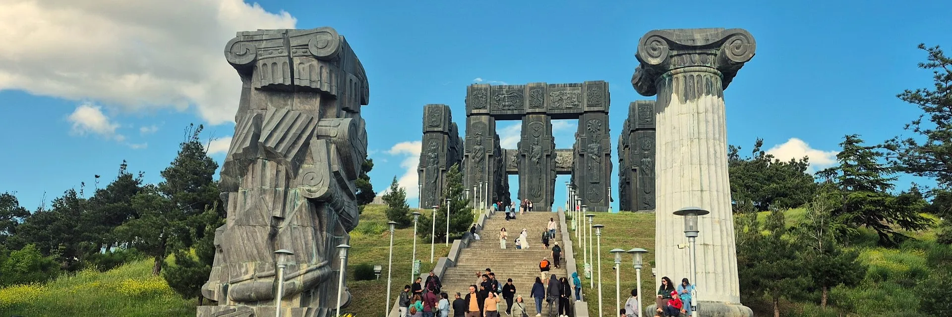 The Chronicle of Georgia monument on a sunny day with green hills and blue sky.