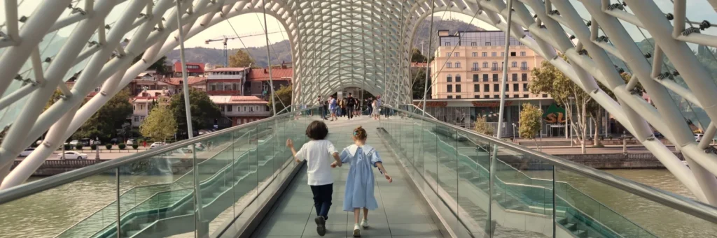 Two children running inside the modern Bridge of Peace in Tbilisi, Georgia
