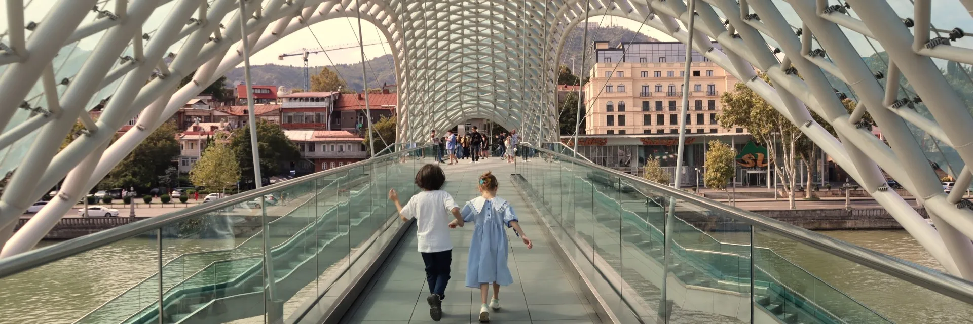 Two children running inside the modern Bridge of Peace in Tbilisi, Georgia