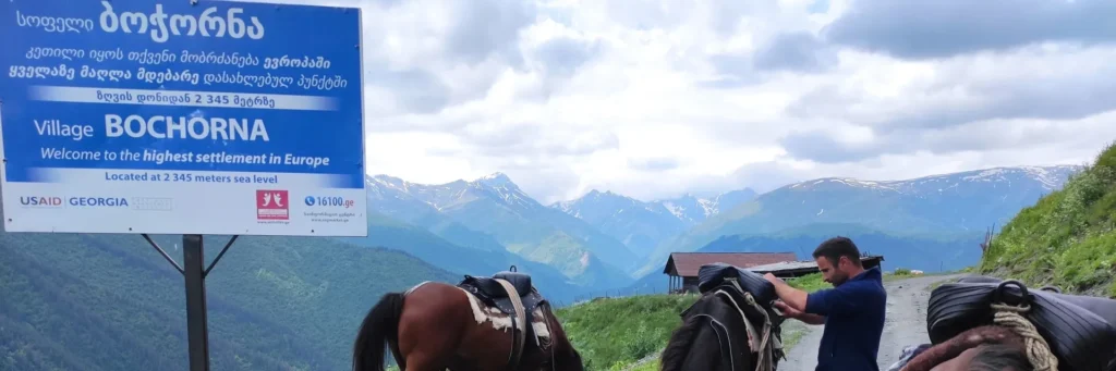 he official welcome sign of Bochorna village with horses and a guide preparing for a trek