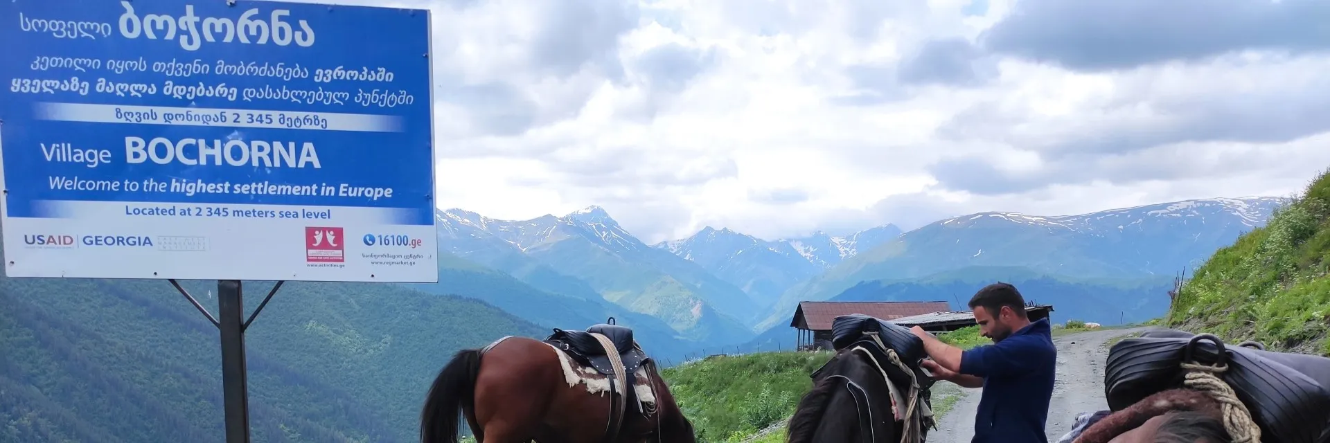 he official welcome sign of Bochorna village with horses and a guide preparing for a trek