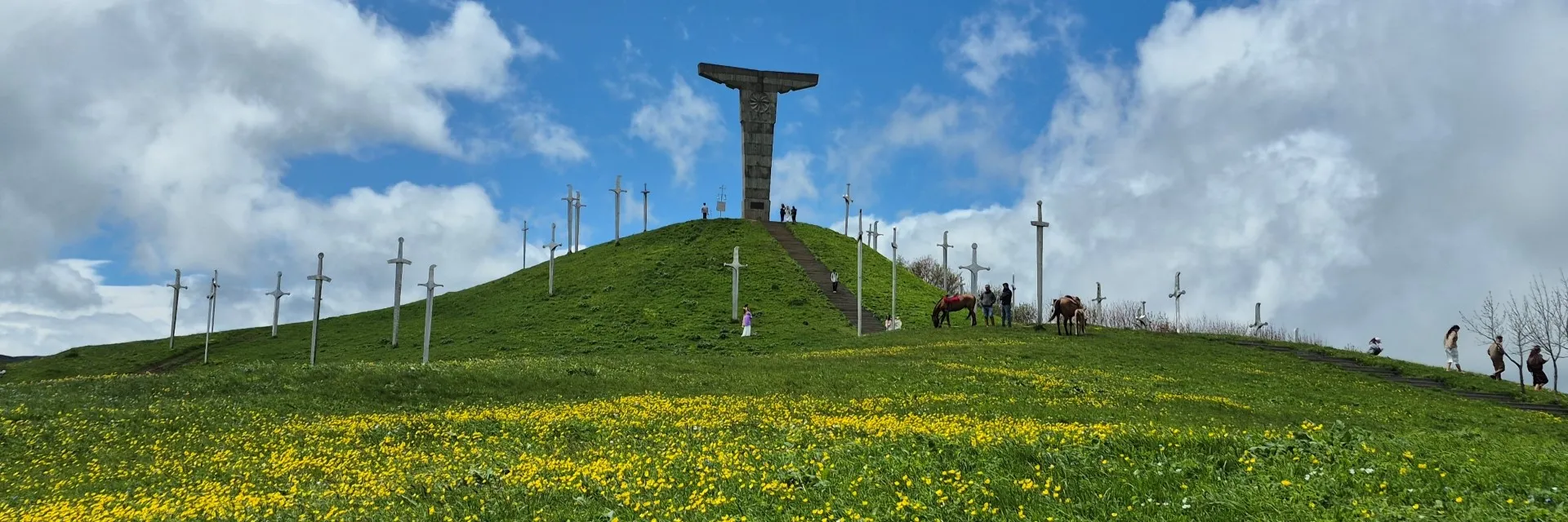 Didgori Battle Memorial monument hill with giant iron swords, horses, and yellow wildflowers