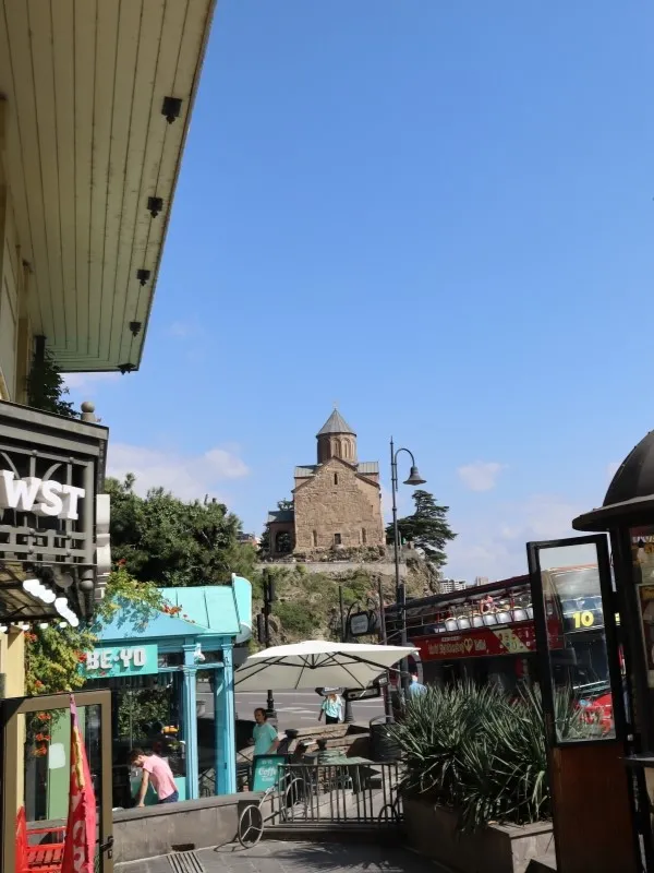 The stone structure of Metekhi Church framed by buildings on Europe Square