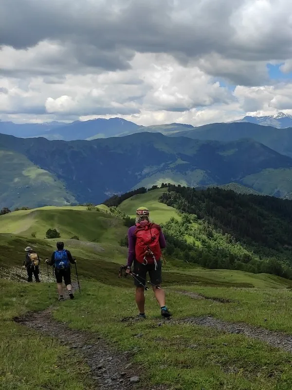 Hikers with backpacks trekking along a scenic ridge trail in Tusheti mountains