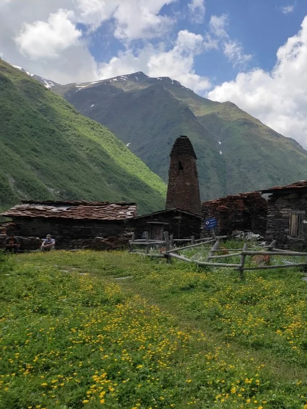 An ancient stone defensive tower in Parsma village surrounded by a field of yellow wildflowers