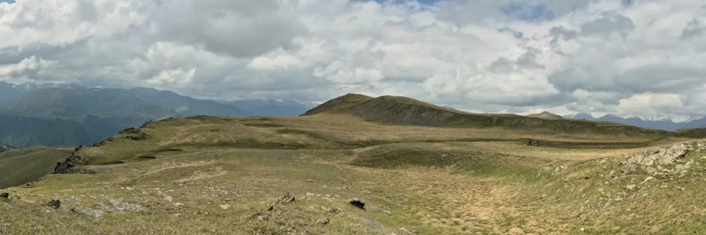 A wide panoramic landscape of the rolling alpine meadows along the Unagira Ridge in Tusheti