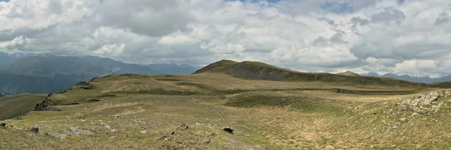 A wide panoramic landscape of the rolling alpine meadows along the Unagira Ridge in Tusheti