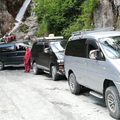 4WD off-road vehicles and travelers on a rugged mountain road during a 3-day Tusheti jeep tour.