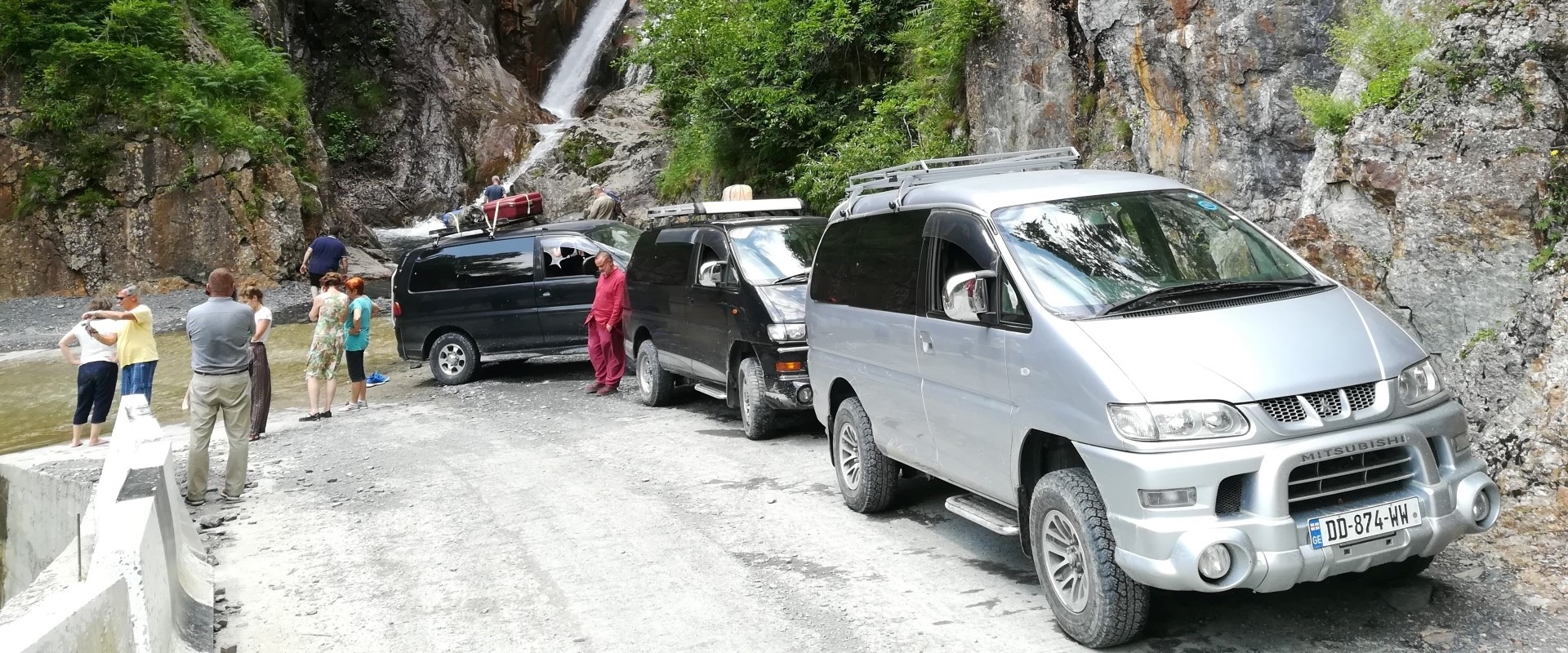 4WD off-road vehicles and travelers on a rugged mountain road during a 3-day Tusheti jeep tour.