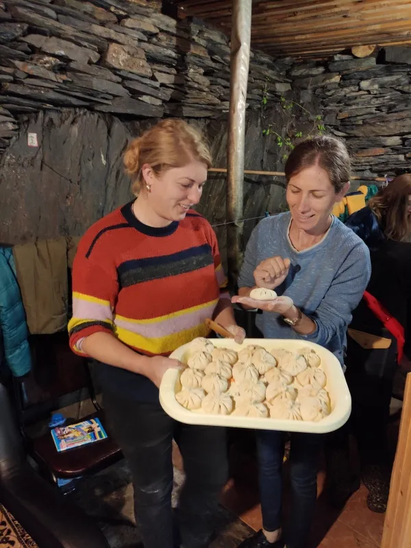 Travelers learning to fold authentic Tushetian food and khinkali inside a stone mountain house